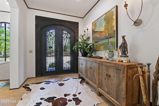 entrance foyer with french doors, ornamental molding, arched walkways, baseboards, and stone finish floors