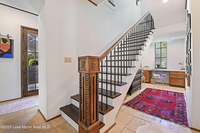 staircase featuring a high ceiling, stone tile flooring, recessed lighting, and baseboards