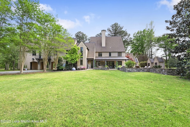 rear view of house featuring stucco siding, a yard, and a chimney