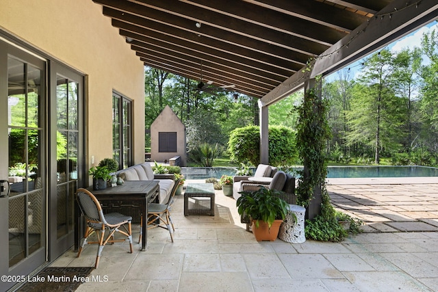 view of patio / terrace with outdoor lounge area, an outdoor pool, and view of wooded area