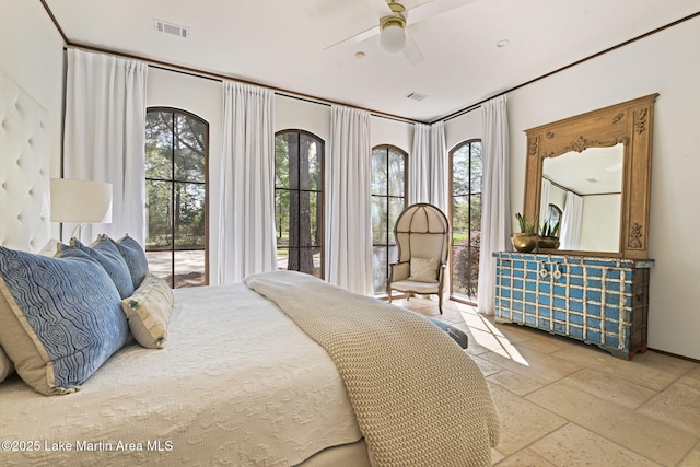 bedroom with multiple windows, stone tile flooring, and a ceiling fan