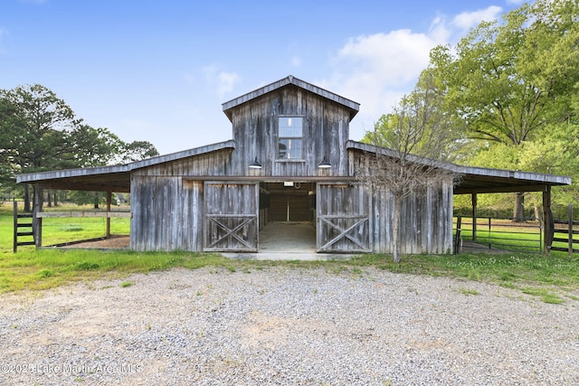 view of barn featuring fence and an exterior structure