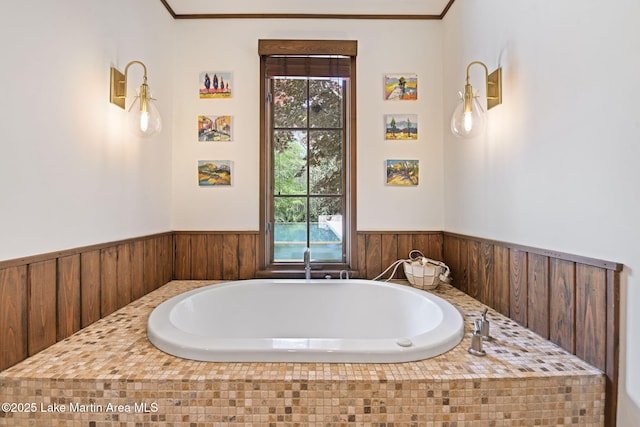 bathroom with wainscoting, a bath, and ornamental molding
