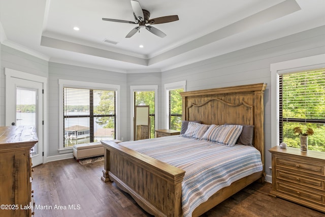 bedroom with dark hardwood / wood-style floors, ceiling fan, and a tray ceiling