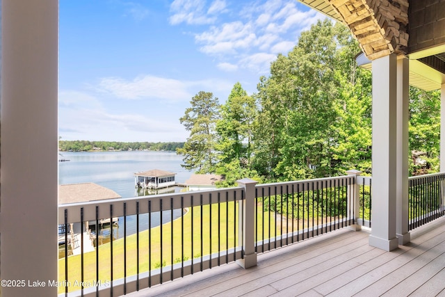 wooden terrace with a water view and a yard