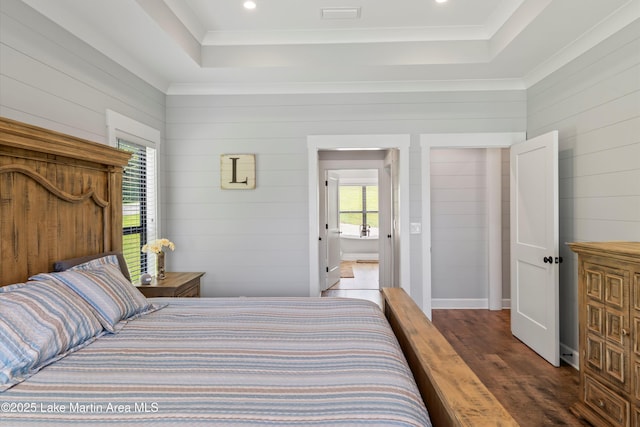 bedroom featuring ornamental molding, dark hardwood / wood-style flooring, and a tray ceiling