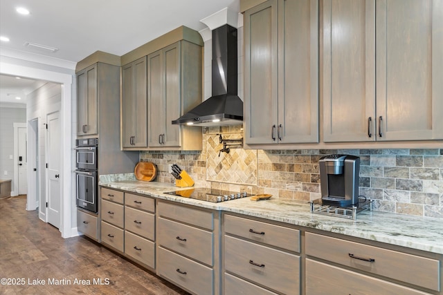 kitchen featuring wall chimney range hood, light stone countertops, and black appliances