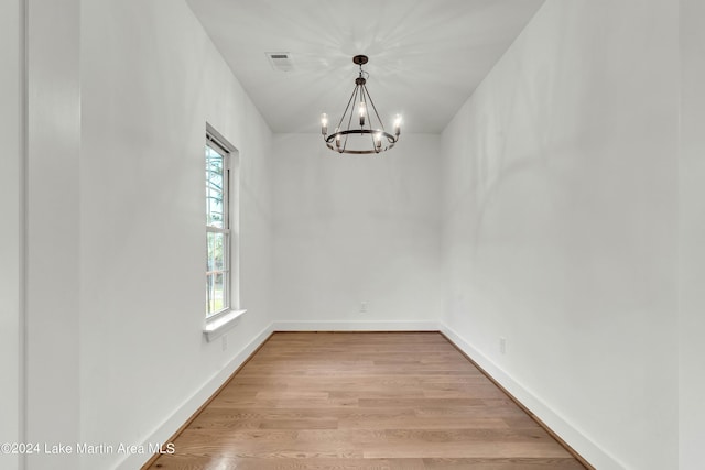 unfurnished dining area with a wealth of natural light, a chandelier, and light wood-type flooring