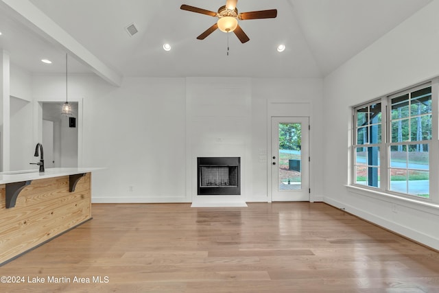 unfurnished living room featuring high vaulted ceiling, sink, hardwood / wood-style flooring, ceiling fan, and beam ceiling