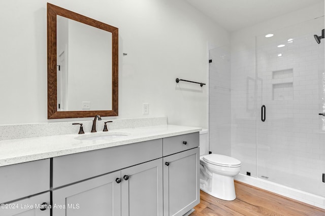 bathroom with walk in shower, hardwood / wood-style floors, vanity, and toilet