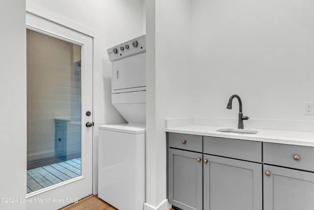 laundry room featuring light hardwood / wood-style floors, sink, and stacked washer and clothes dryer