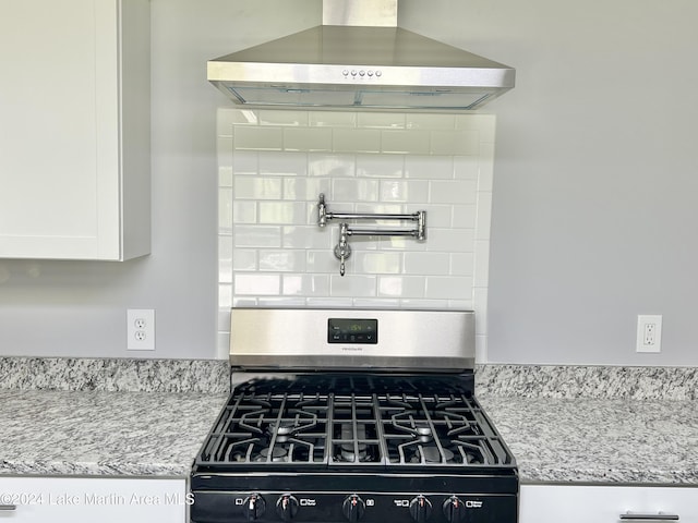 kitchen featuring white cabinets, light stone countertops, wall chimney exhaust hood, and stainless steel range with gas stovetop