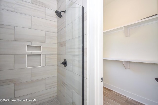 full bathroom with a stall shower, wood finished floors, and baseboards