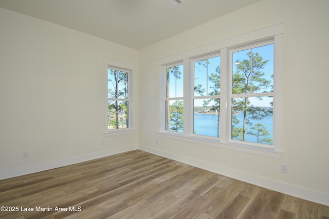 unfurnished room with wood finished floors, visible vents, and baseboards