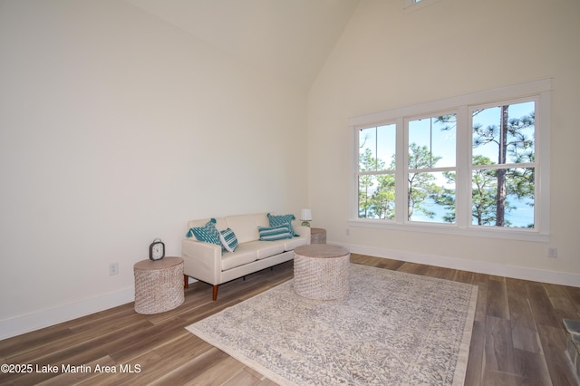 sitting room featuring high vaulted ceiling, dark wood-style flooring, and baseboards