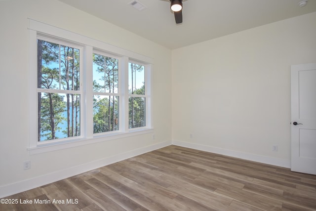 empty room featuring baseboards, visible vents, ceiling fan, and wood finished floors