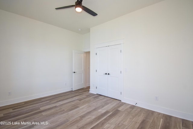 unfurnished bedroom featuring a closet, wood finished floors, a ceiling fan, and baseboards