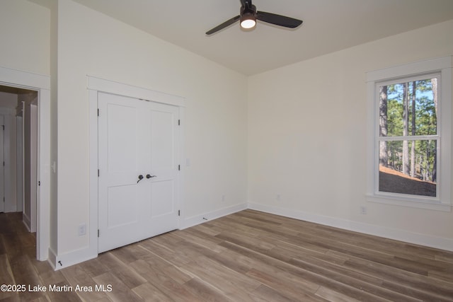 unfurnished room featuring ceiling fan, baseboards, and wood finished floors