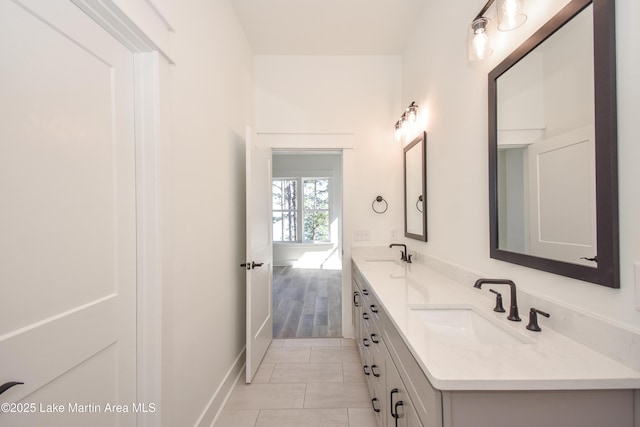 bathroom featuring baseboards, double vanity, a sink, and tile patterned floors