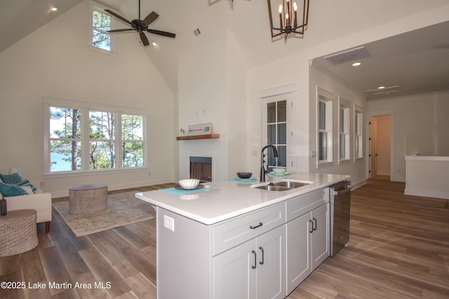 kitchen featuring visible vents, open floor plan, a sink, a fireplace, and stainless steel dishwasher