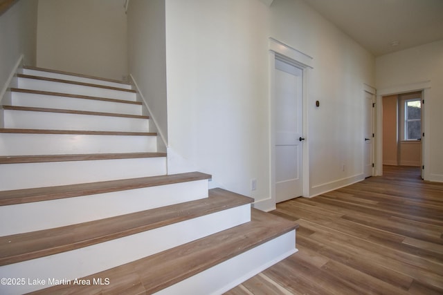 staircase featuring baseboards and wood finished floors