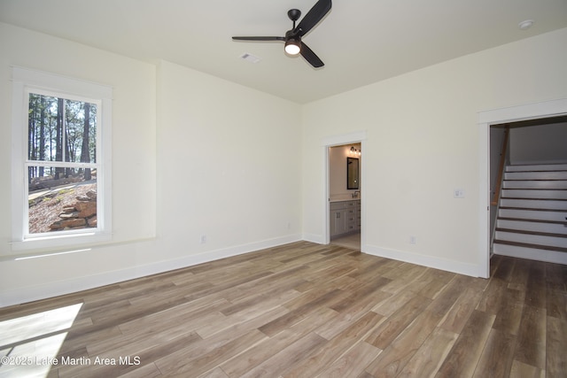 unfurnished bedroom with a walk in closet, visible vents, connected bathroom, light wood-type flooring, and baseboards