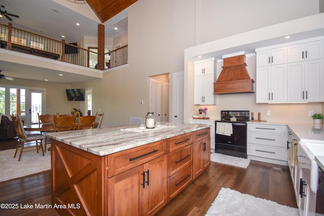 kitchen featuring a ceiling fan, custom exhaust hood, open floor plan, high vaulted ceiling, and black electric range