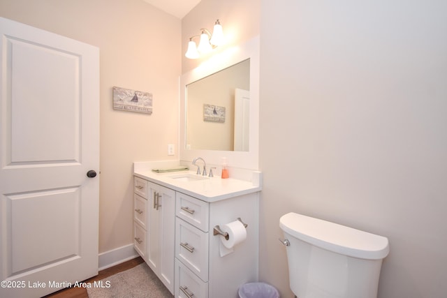 bathroom with vanity, toilet, baseboards, and wood finished floors