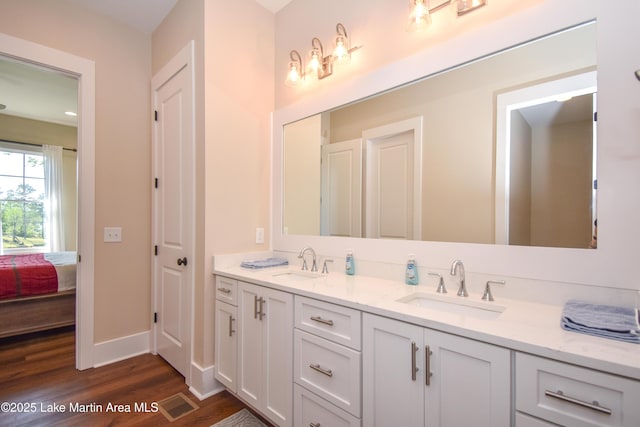 ensuite bathroom with ensuite bath, double vanity, a sink, and wood finished floors
