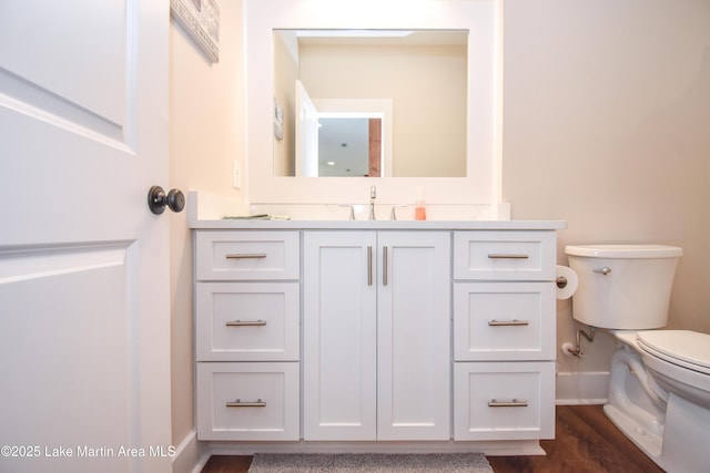 bathroom featuring vanity, toilet, baseboards, and wood finished floors