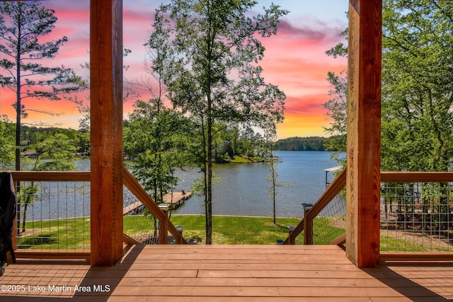 deck at dusk with a yard and a water view