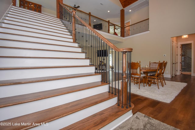 staircase with a towering ceiling, baseboards, recessed lighting, and wood finished floors