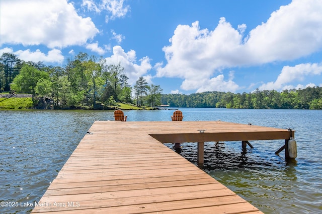 view of dock featuring a wooded view and a water view