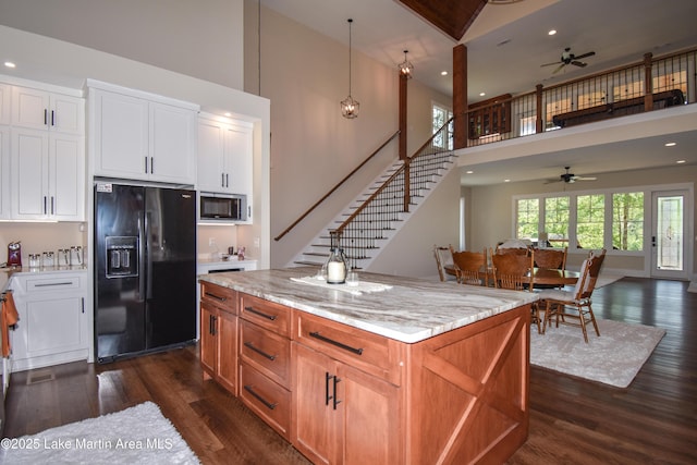 kitchen with a high ceiling, stainless steel microwave, ceiling fan, and black refrigerator with ice dispenser