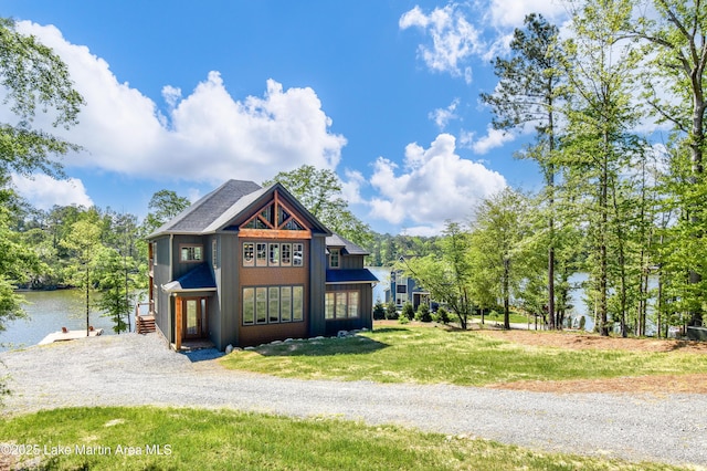 view of front facade featuring a water view, a front lawn, and gravel driveway