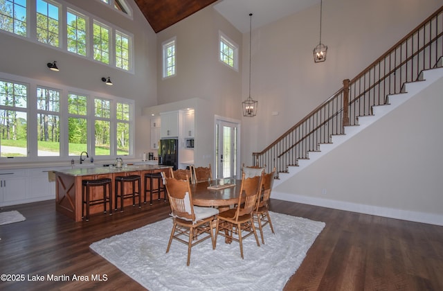 dining room featuring stairs, dark wood-style flooring, baseboards, and high vaulted ceiling