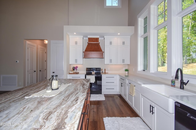 kitchen with black appliances, plenty of natural light, visible vents, and a high ceiling