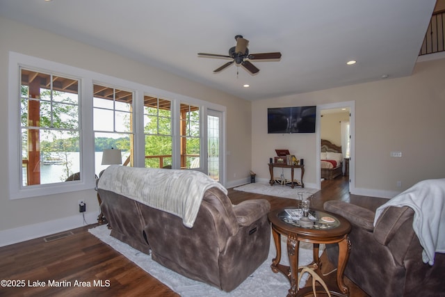 living room with baseboards, a ceiling fan, visible vents, and wood finished floors
