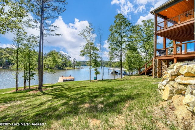 view of yard with stairs, a deck with water view, and a floating dock