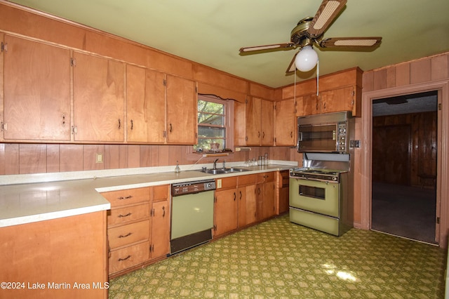 kitchen with gas range, wood walls, dishwasher, and sink