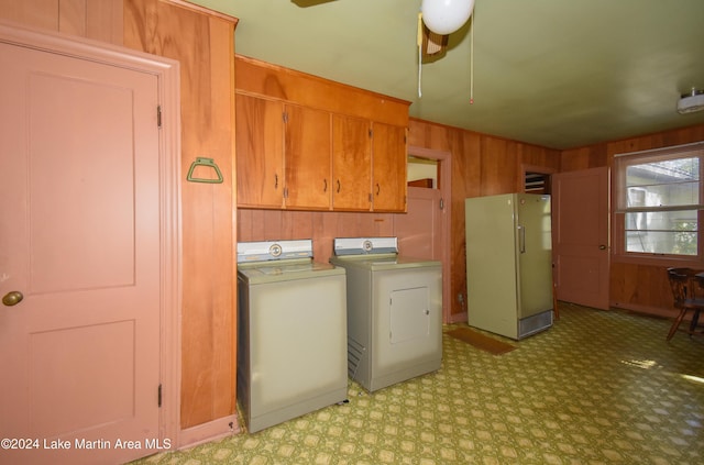 laundry room with cabinets, washing machine and dryer, and wooden walls