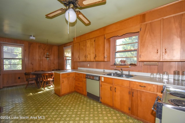 kitchen featuring stove, ceiling fan, wooden walls, sink, and dishwasher