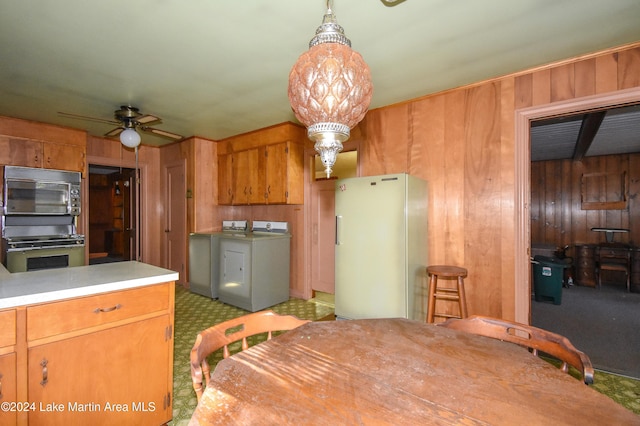 kitchen with ceiling fan, wood walls, carpet floors, white fridge, and decorative light fixtures