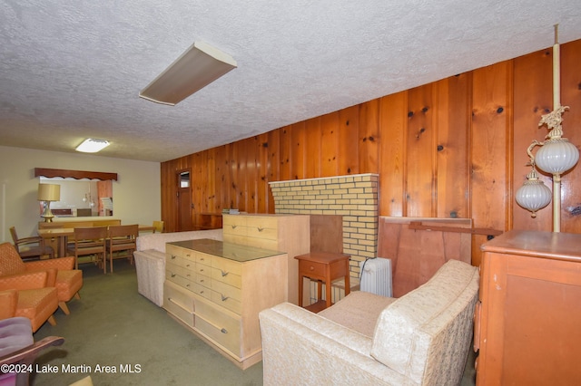 living area featuring a textured ceiling, dark carpet, and wood walls