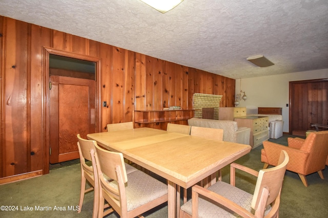 dining space featuring a textured ceiling, dark carpet, and wooden walls