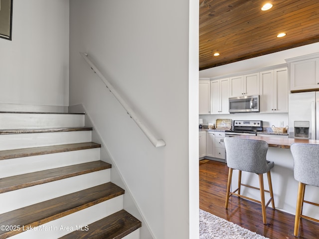 stairway featuring wood-type flooring and wooden ceiling