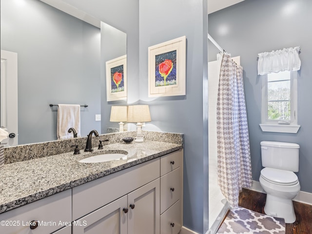 bathroom featuring hardwood / wood-style floors, vanity, curtained shower, and toilet