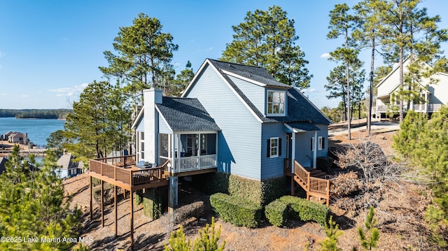 view of side of home featuring a deck with water view and a sunroom