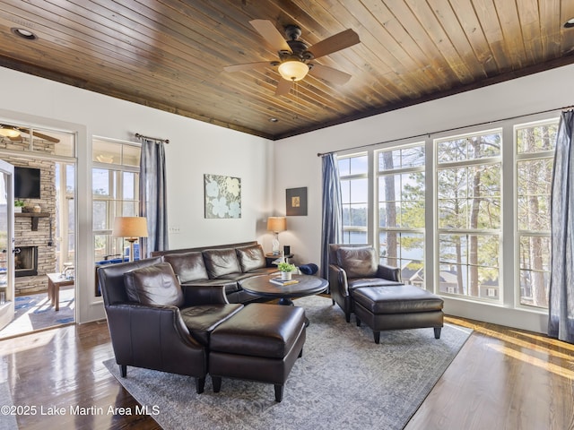 living room featuring hardwood / wood-style flooring, a stone fireplace, and wooden ceiling