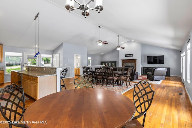 310 Hillwood, Dadeville, AL 36853 - dining area featuring a fireplace, vaulted ceiling, light wood-style floors, a ceiling fan, and a chandelier
